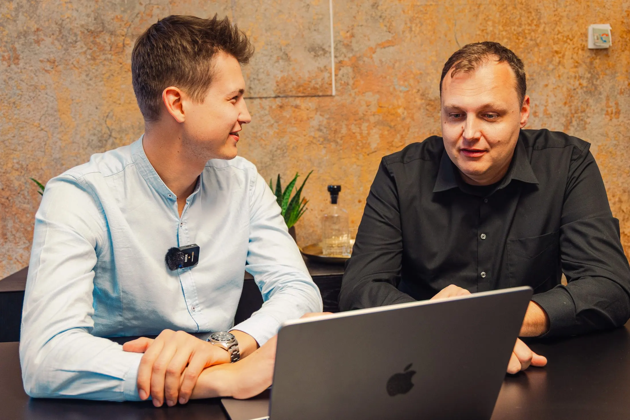 Zwei Kaino-Mitarbeiter besprechen sich an einem Tisch mit Laptop